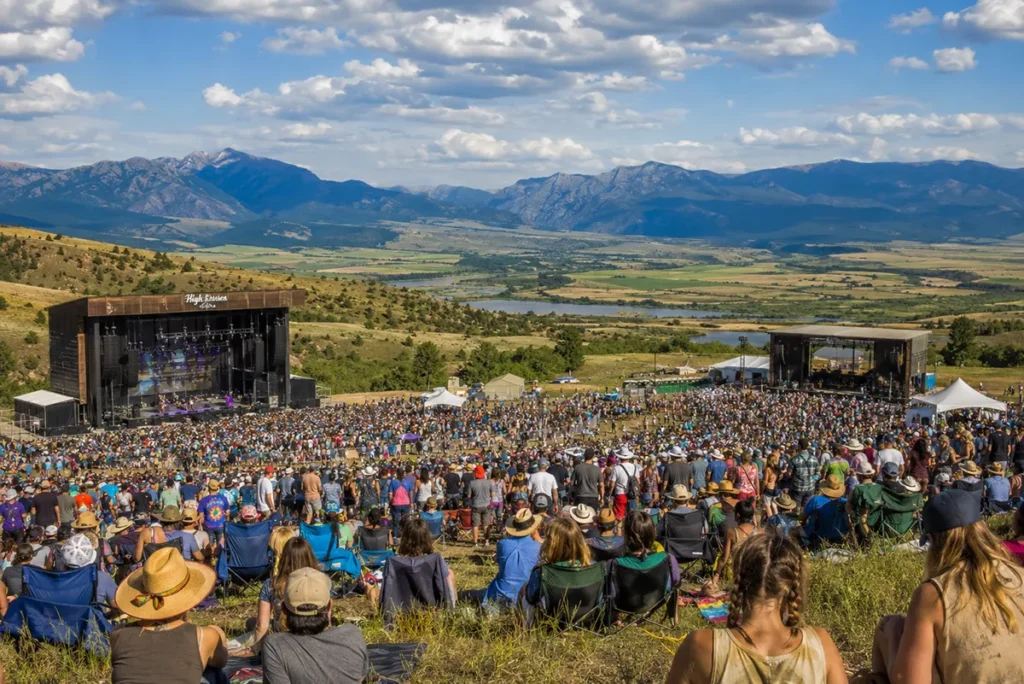 Under the Big Sky Music Festival crowd on a Montana ranch near Whitefish with mountain backdrop and two stages visible