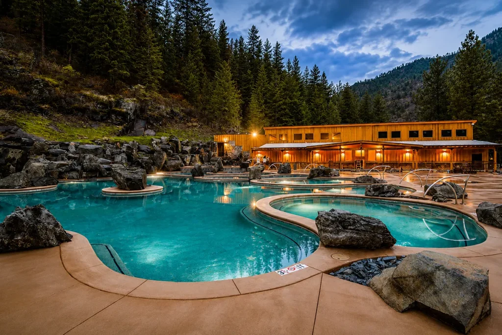 Aerial view of Quinn's Hot Springs Resort nestled along the Clark Fork River with forested mountains in background