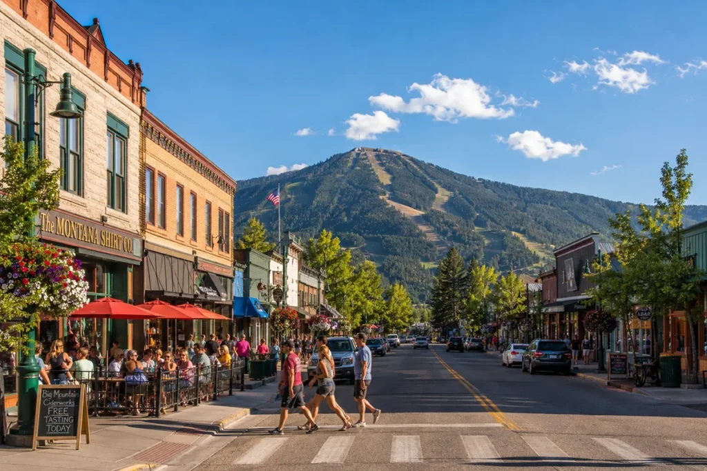 Whitefish Montana downtown Central Avenue in summer with Whitefish Mountain Resort visible in the background and people on the sidewalk