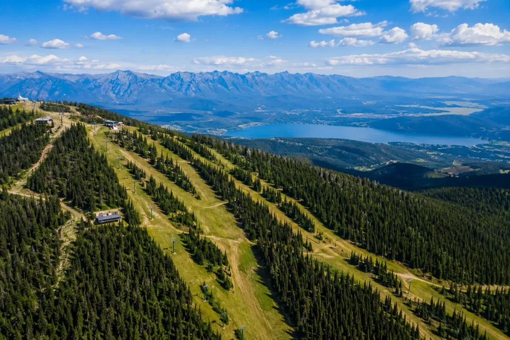 Whitefish Mountain Resort aerial view in summer with ski runs and Whitefish Lake visible below