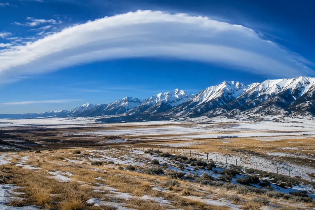 Open ranchland along the Rocky Mountain Front near Choteau, Montana with snow melting and Chinook arch visible in sky
