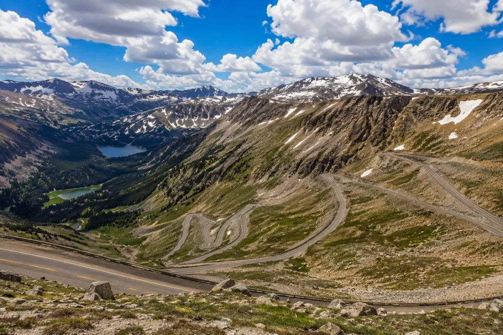 Beartooth Highway switchbacks climbing to 11,000 feet with snow-capped peaks and alpine lakes visible