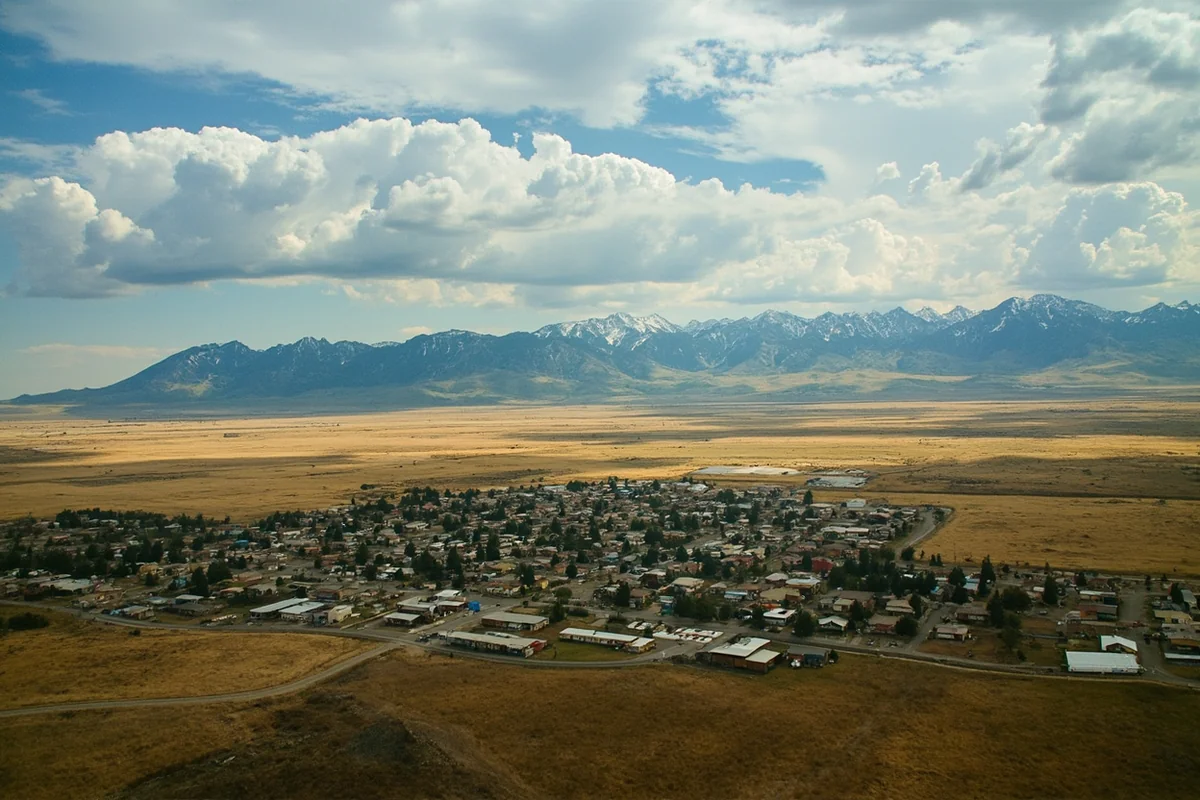 Aerial view of a small Montana town surrounded by mountains and prairie, showcasing the isolated beauty that contributes to safety