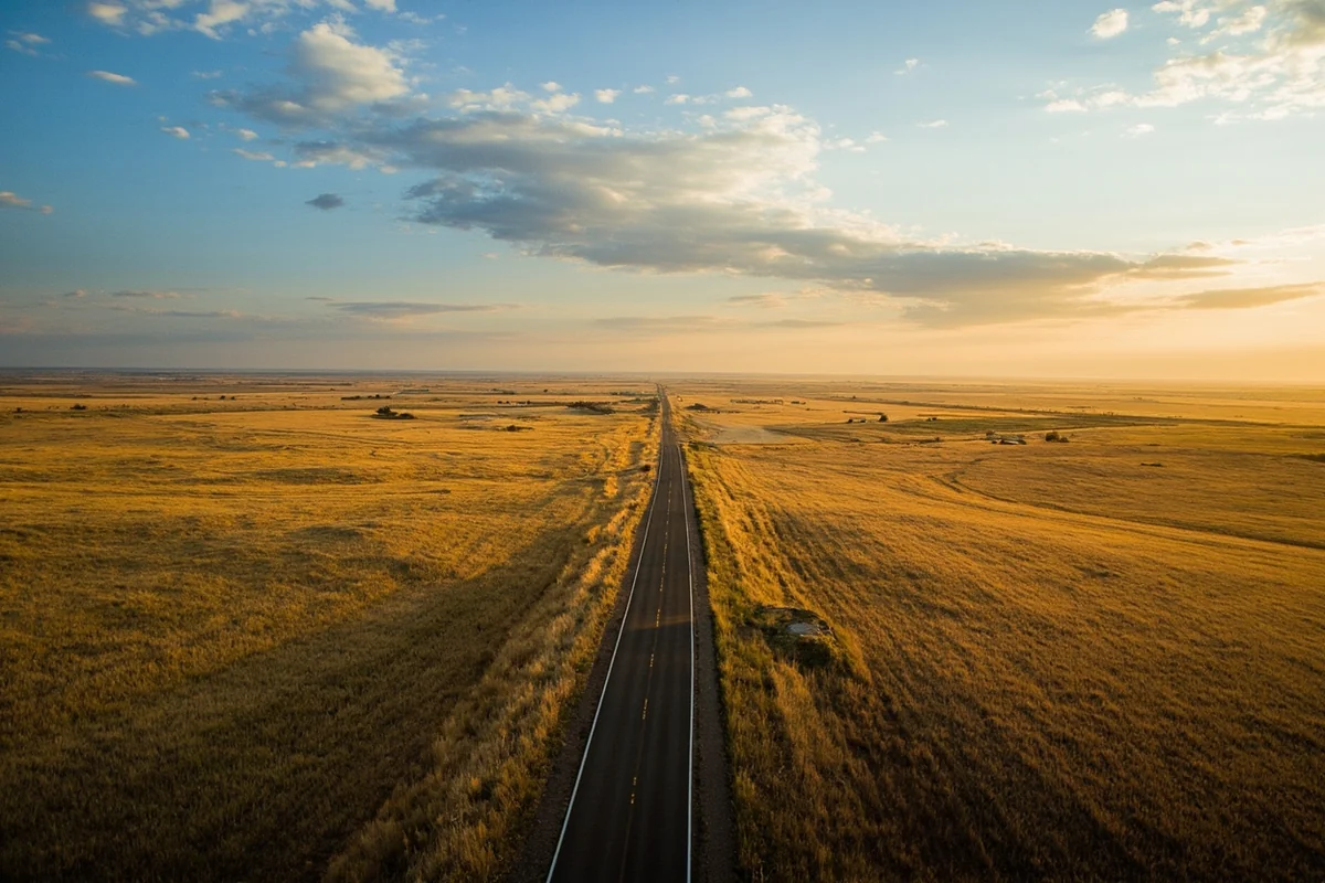 Aerial view of vast Montana prairie with a single road stretching to the horizon