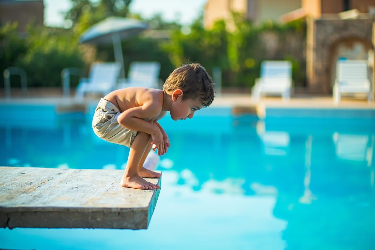 Child preparing to jump from the diving board into the deep end pool