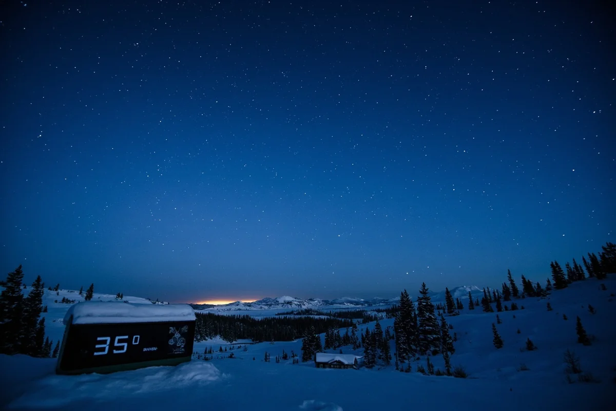 Clear starry night sky over snow-covered Flathead Valley with temperature display showing below-zero reading
