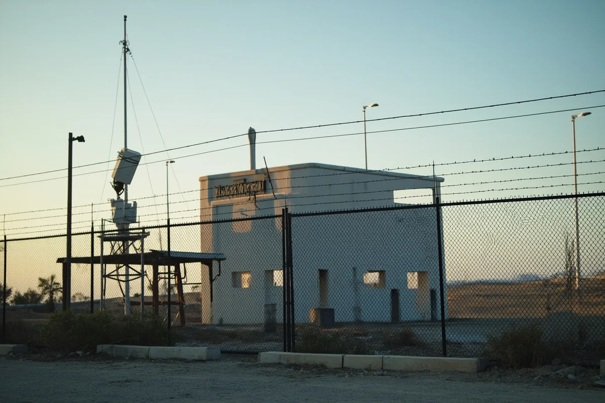 Close-up of a decommissioned Launch Control Facility showing the support building and communication equipment behind security fencing