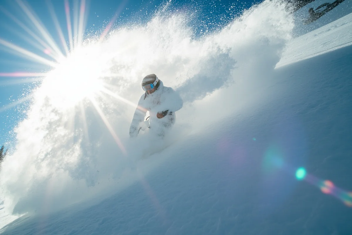 Close-up of powder spray behind skier with sun creating rainbow effect through snow crystals