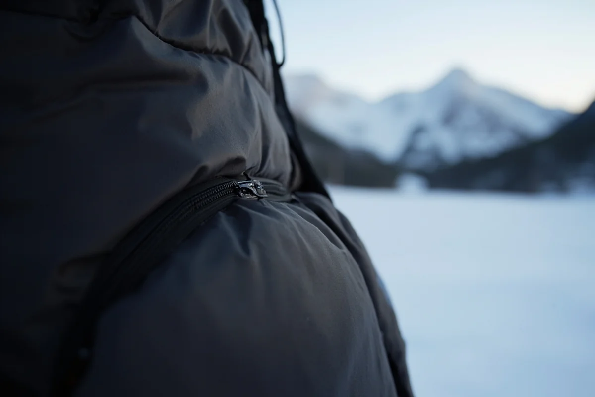 Close-up of quality down puffy jacket showing baffles and fill, with Montana winter landscape in background