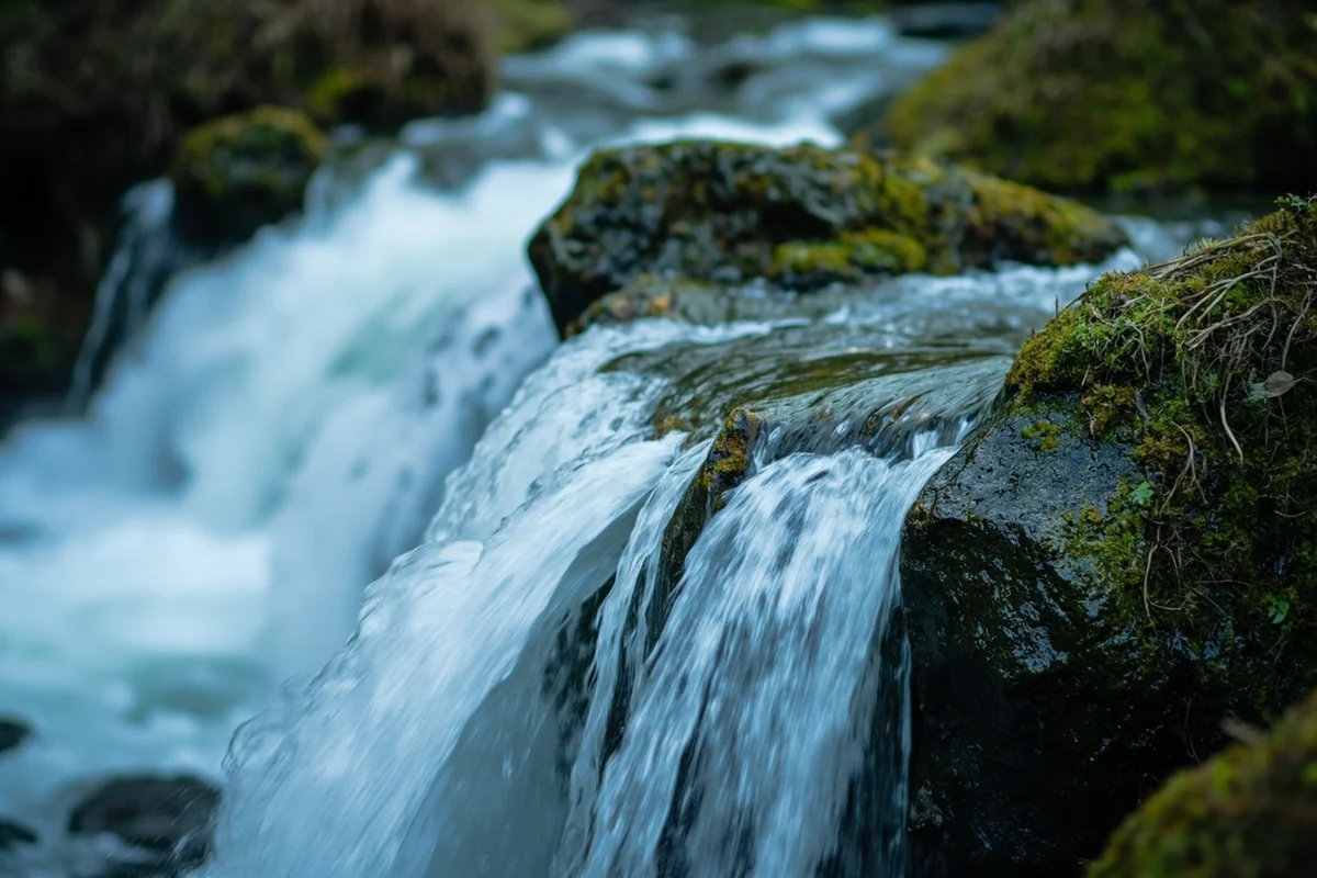 Close-up of Rainbow Falls cascade showing water texture and moss-covered rocks, shot with slow shutter speed