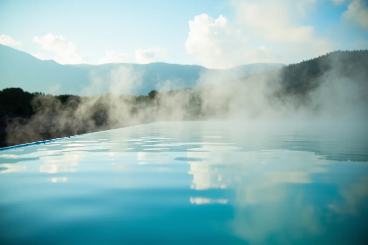 Close-up of the hot therapy pool with steam rising and mountains visible in distance