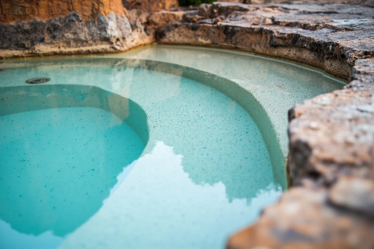 Close-up of the main soaking pool showing the mineral-tinted water and rock formations