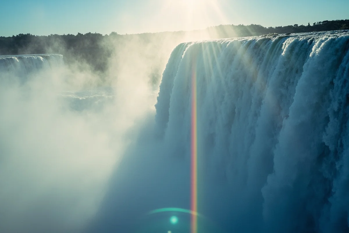 Close-up of waterfall mist with rainbow refraction in morning light
