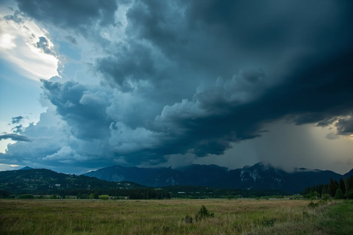 Dramatic afternoon thunderstorm building over Montana mountains with dark clouds and visible rain