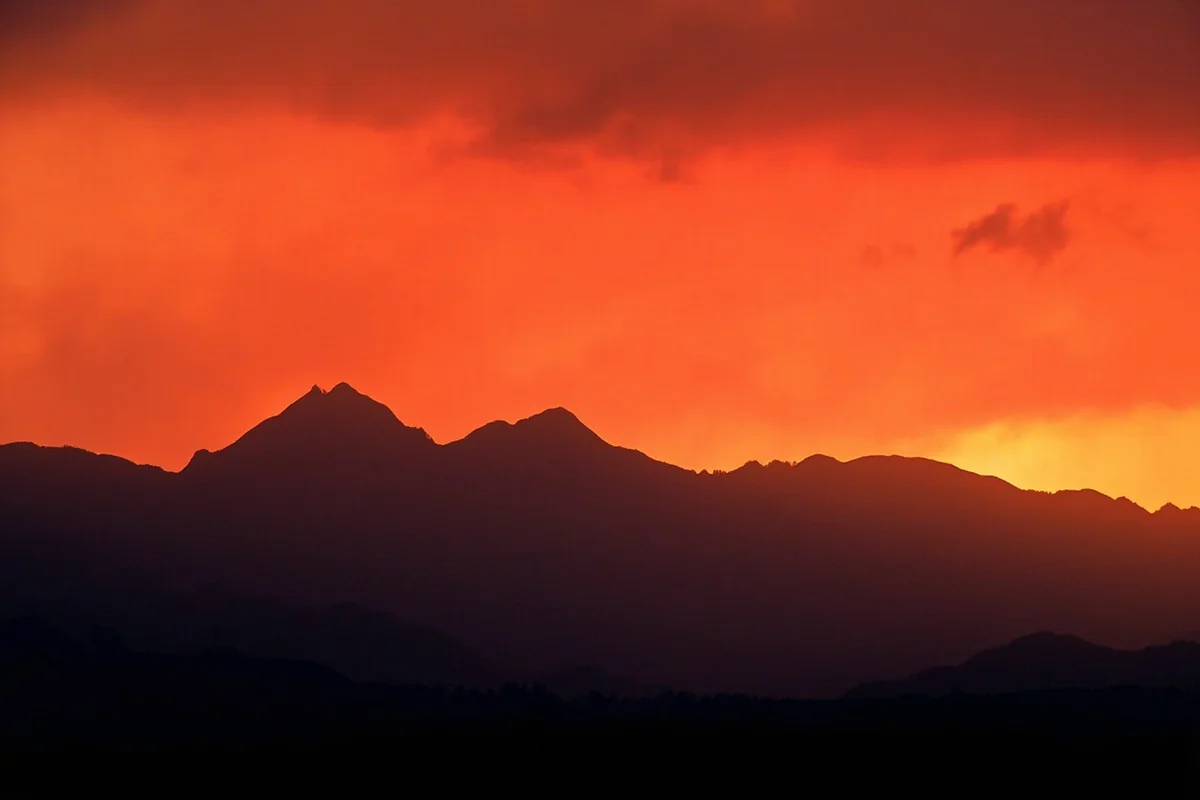 Dramatic orange wildfire smoke obscuring mountain peaks in western Montana at sunset