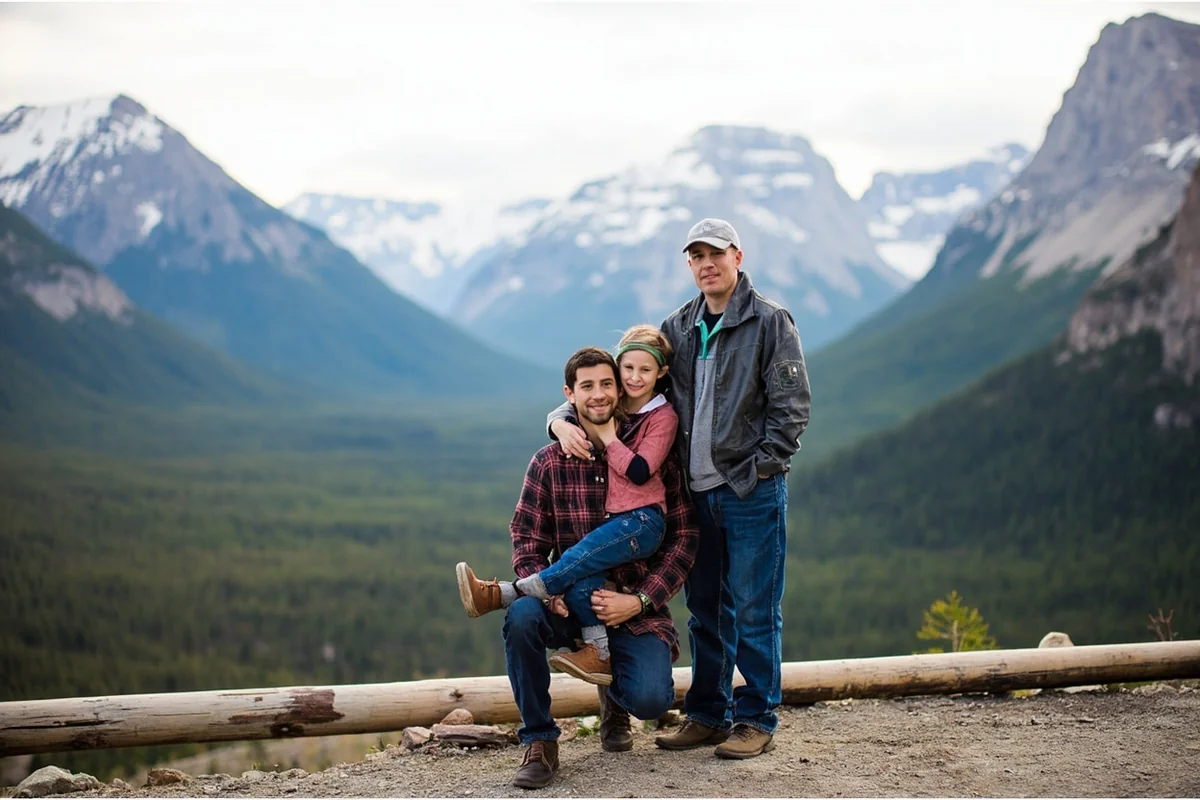 Family standing at Logan Pass overlook in Glacier National Park with mountain peaks in background