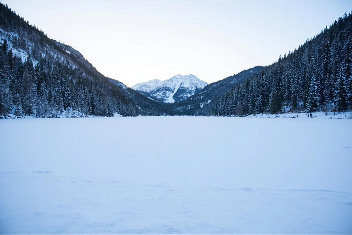 Frozen Seeley Lake in Montana with a cleared ice skating area and snow-covered forest in the background