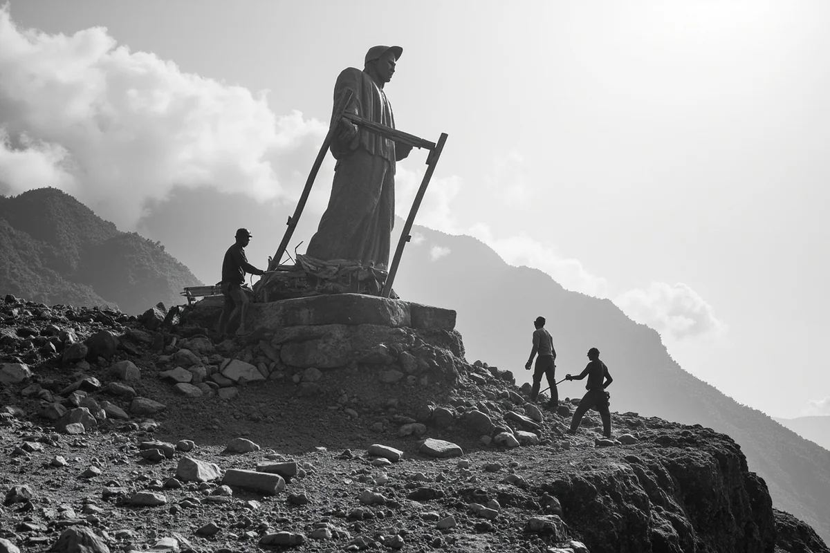 Historical black and white photo of construction workers building the statue frame on the mountain
