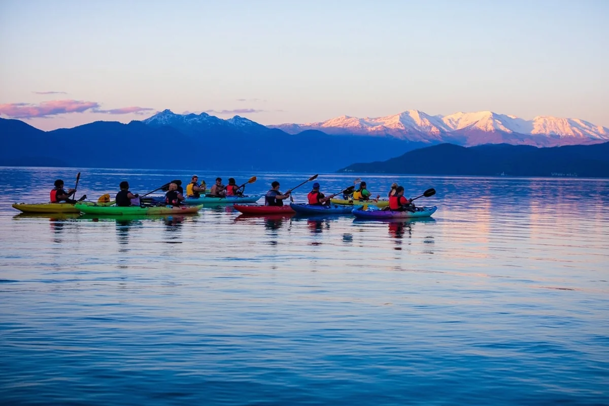 Kayakers on Flathead Lake with Mission Mountains in background during summer evening