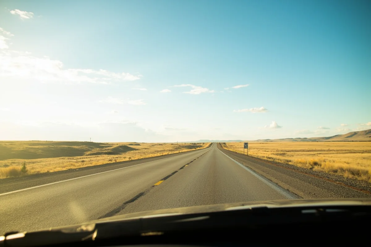 Montana highway stretching through open prairie with speed limit sign visible
