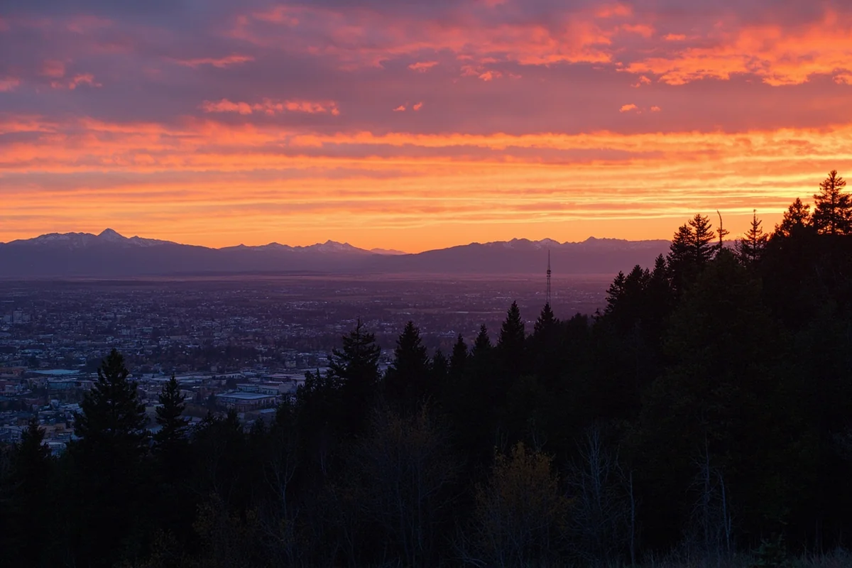 Montana sunset over growing city with mountains in background
