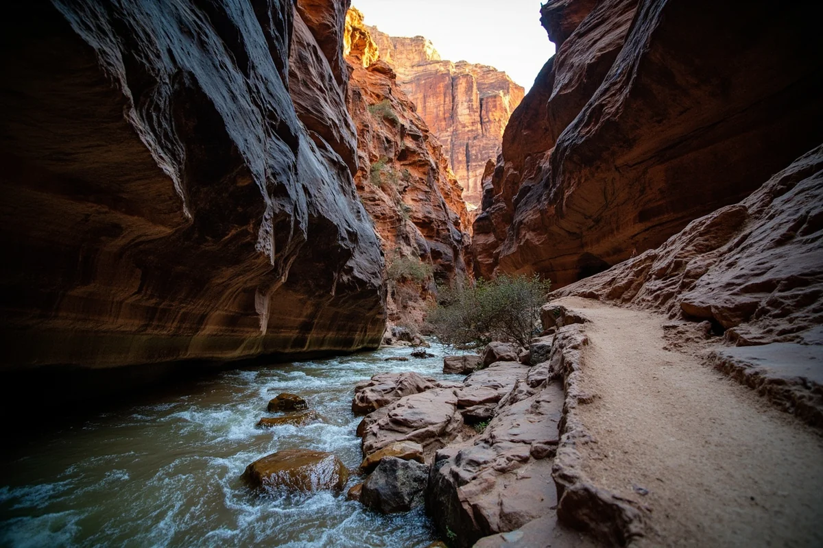 Narrow canyon trail section with rocky terrain and creek visible below