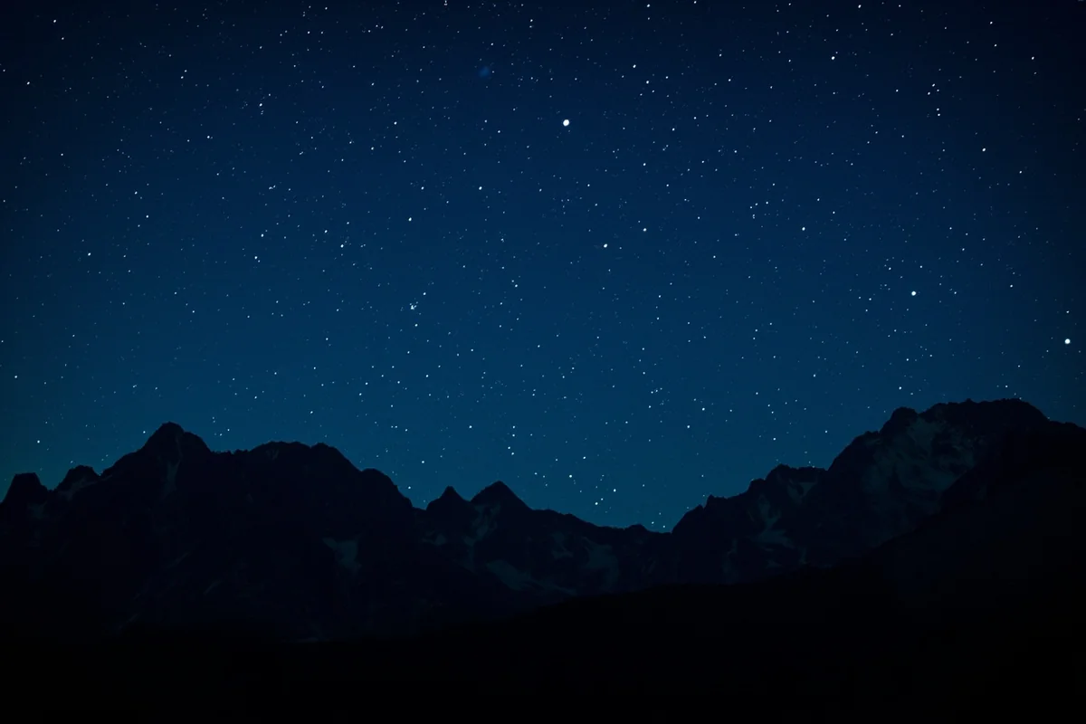 Night sky view from Logan Pass with silhouetted mountain peaks