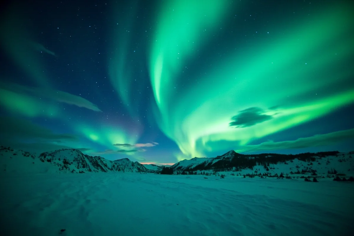 Northern lights dancing over a snow-covered Montana landscape with silhouetted mountains