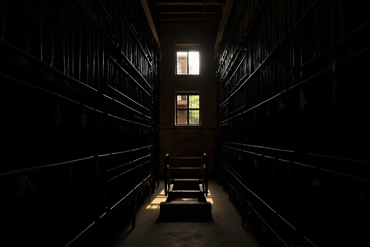Old Montana State Prison cell block showing rows of cells with dramatic lighting casting shadows