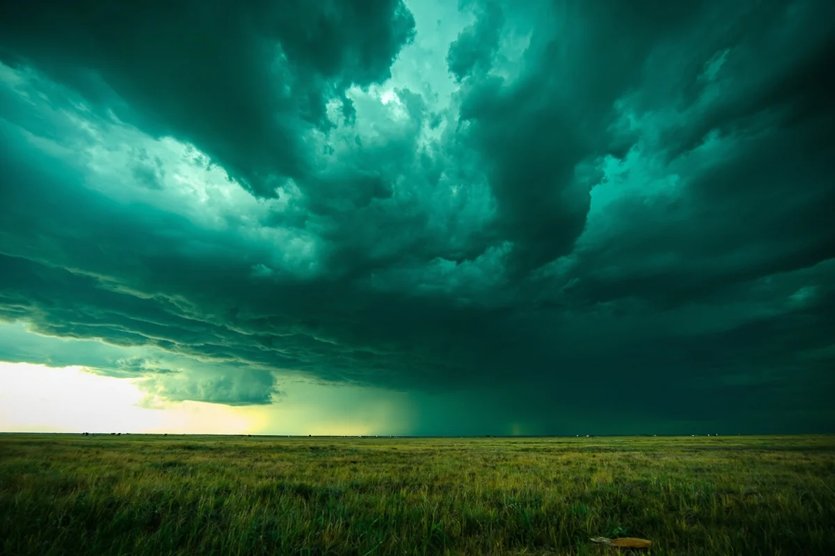 Ominous green-tinted storm clouds over eastern Montana prairie with distant rain shaft