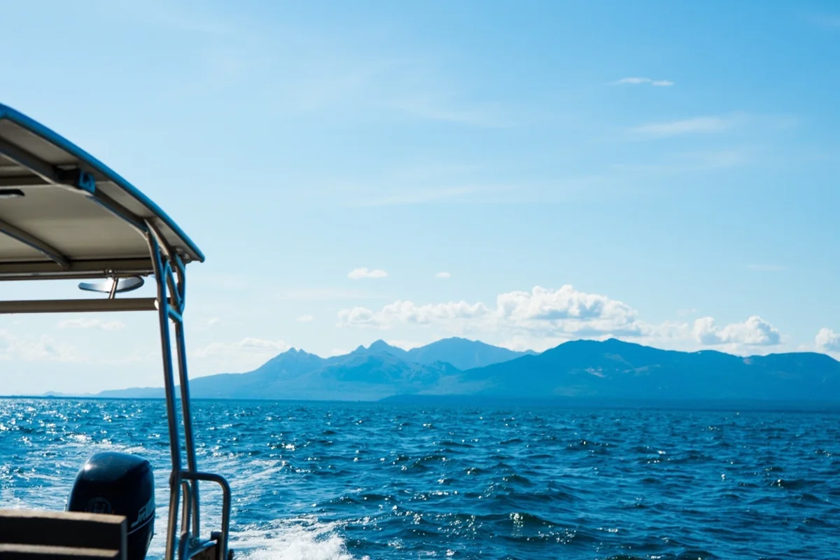 Panoramic view of a boat on Flathead Lake with Mission Mountains in the background