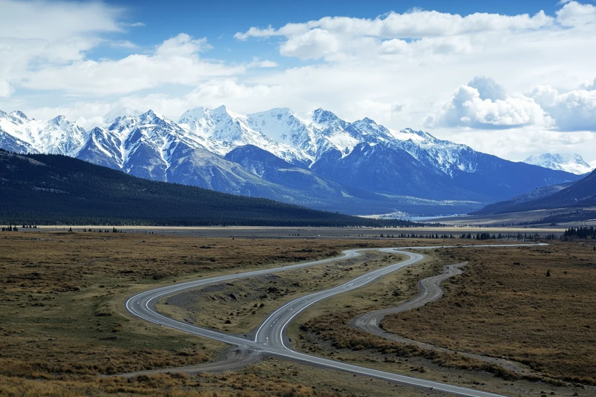 Panoramic view of the Beartooth Highway stretching through mountain passes with snow-capped peaks in the distance