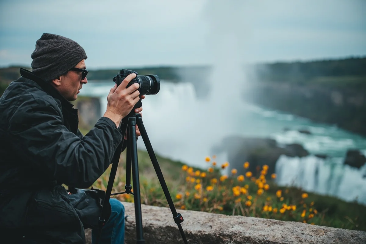 Photographer setting up tripod with view of the falls in background, demonstrating shooting position