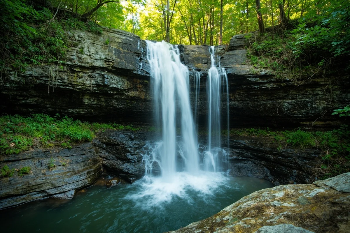 Pinkham Creek Falls cascading down rocky cliff face with lush green vegetation surrounding