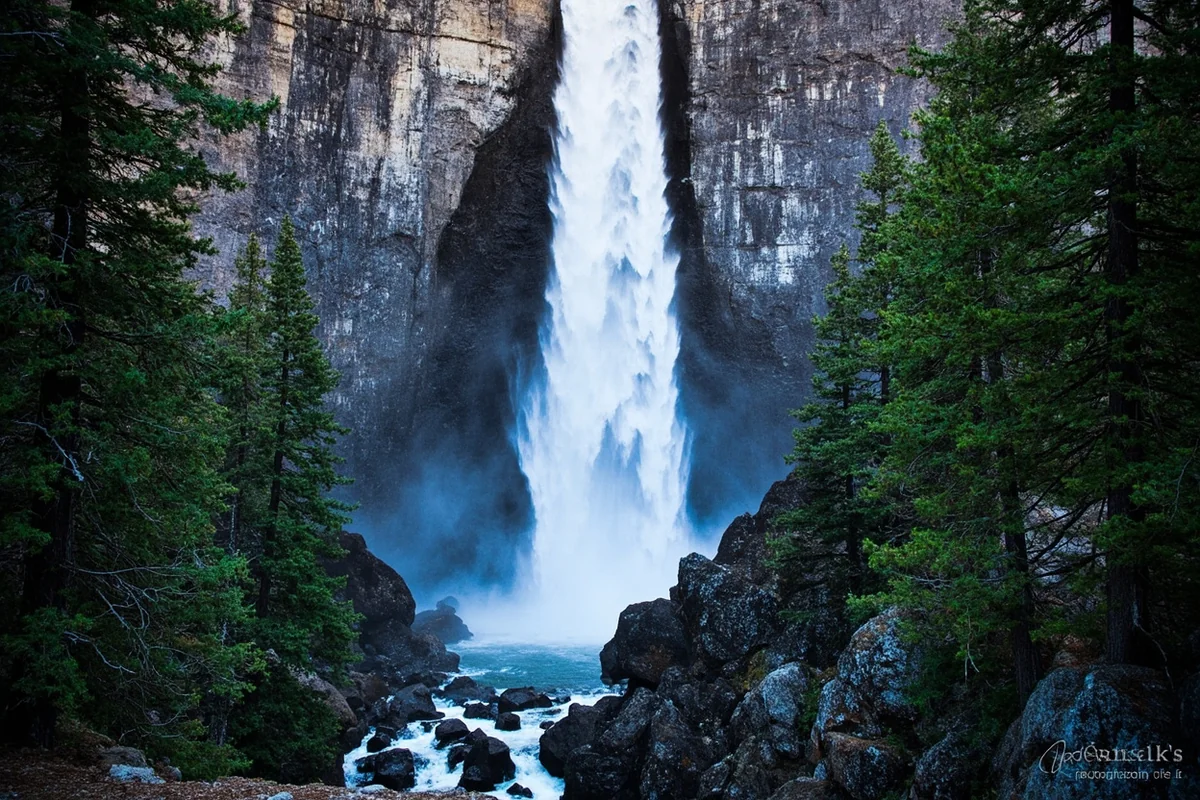 Pintler Falls cascading down granite rock face with evergreen trees framing the sides