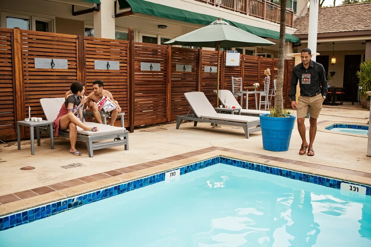 Pool deck area at Quinn's showing loungers, towel hooks, and wooden privacy screens