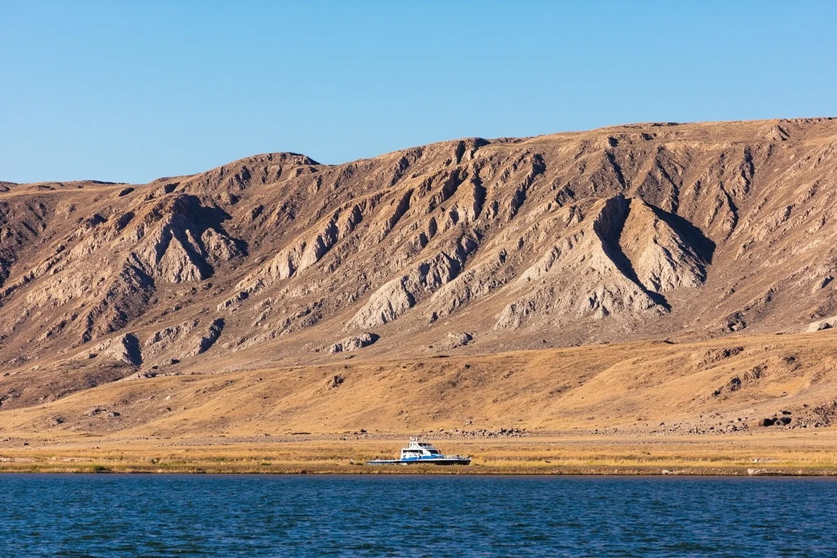 Rugged badlands shoreline at Fort Peck Lake with boat in foreground