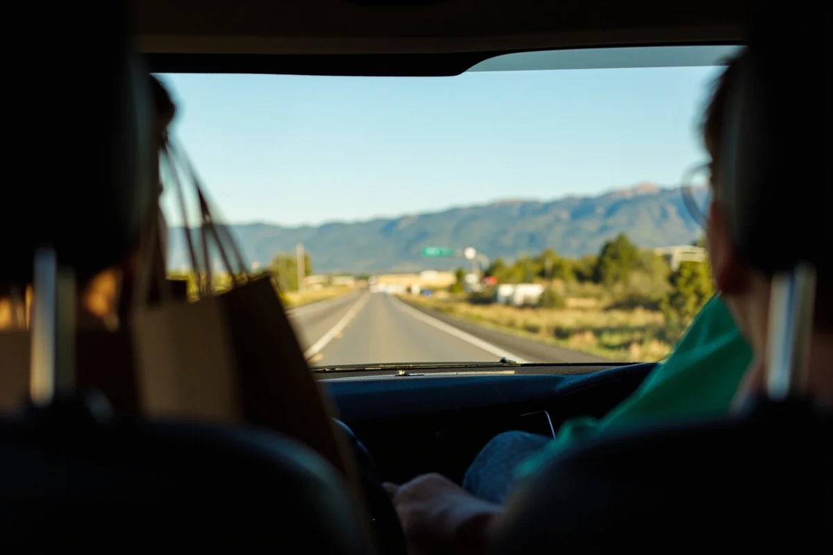 Scenic drive on a Montana highway with shopping bags visible in the back seat of a car, mountains in distance
