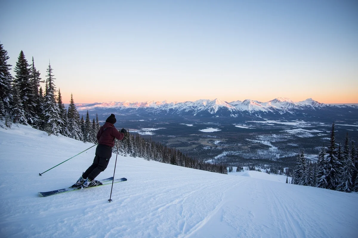Skier on groomed run with stunning Montana mountain range panorama and morning alpenglow