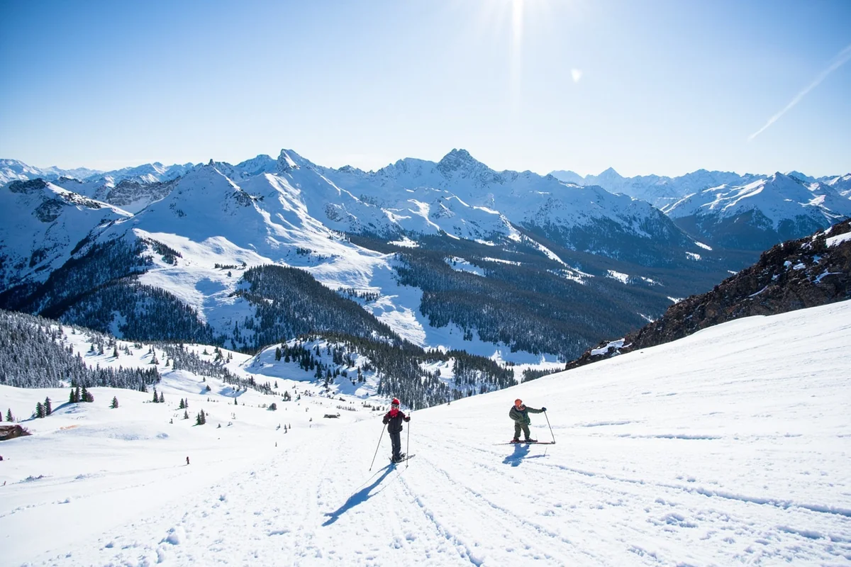 Skiers on a snowy slope at Bridger Bowl with the Bridger Mountains in the background