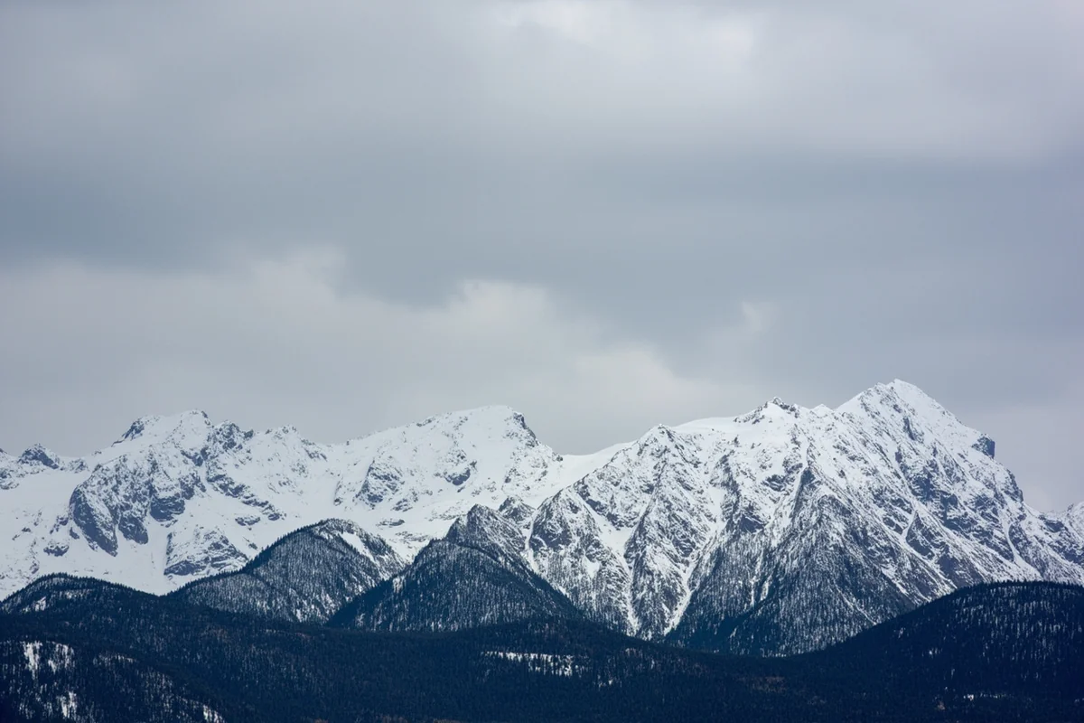 Snow-covered mountain peaks in Montana with dramatic gray November sky