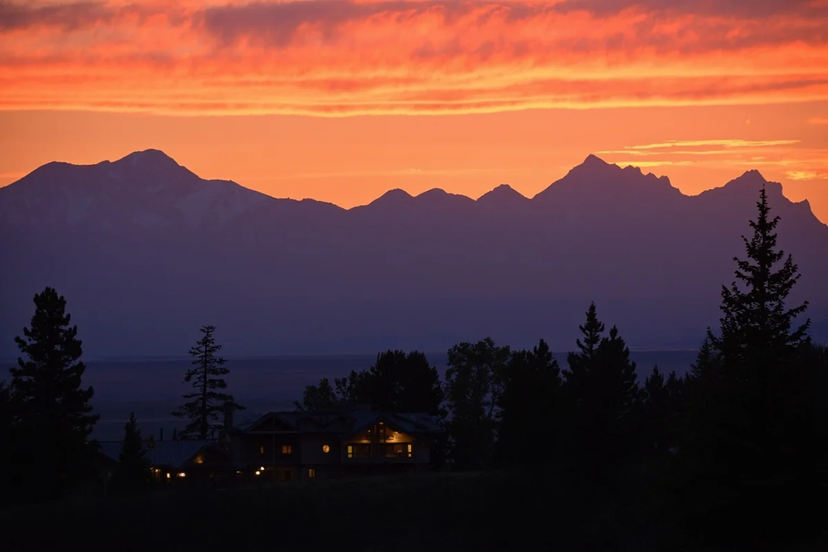 Sunset over Montana mountain range with hunting lodge in foreground