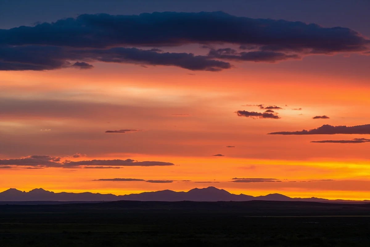 Sunset over Montana plains with dramatic cloud formations and silhouetted mountains