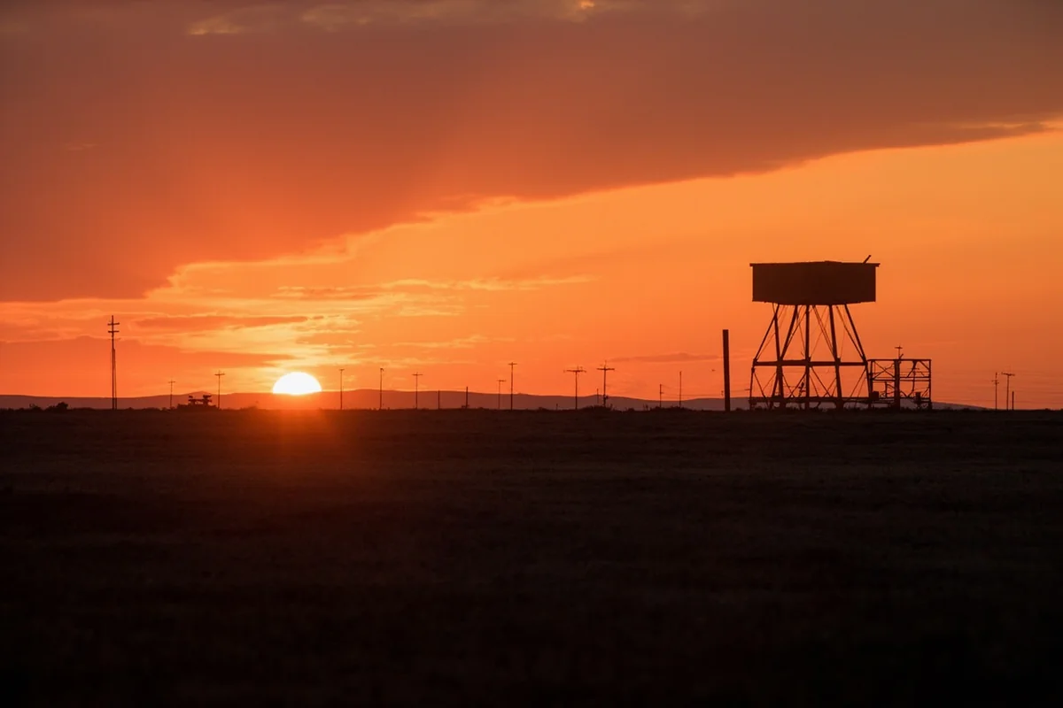 Sunset over Montana prairie with abandoned military structure silhouette, representing the passage of Cold War era