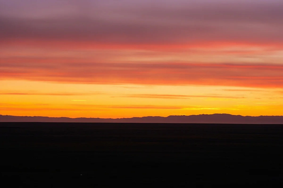 Sunset over Montana prairie with distant mountains and expansive sky