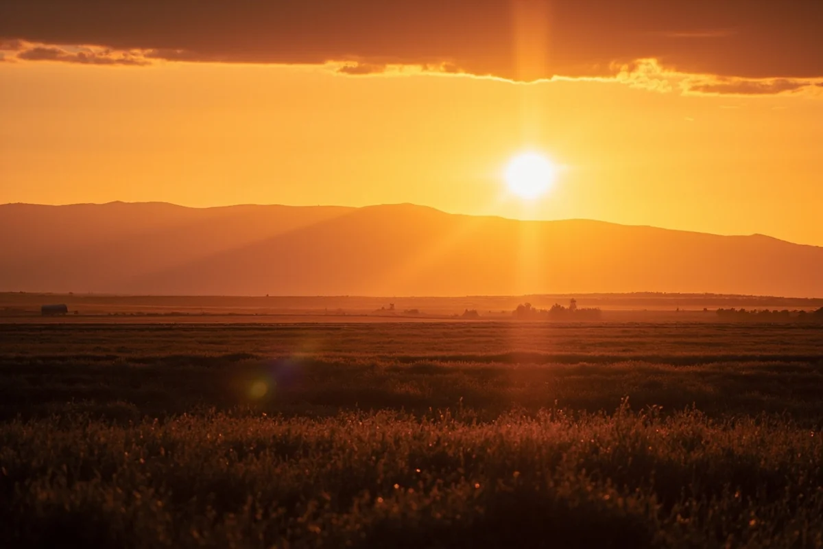 Sunset over Montana prairie with silhouette of distant mountains on horizon