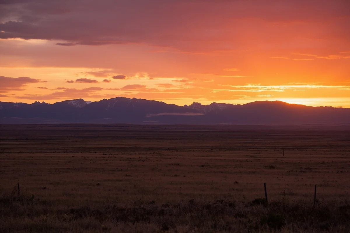 Sunset over Montana's Rocky Mountain Front, with prairie in foreground and mountains behind