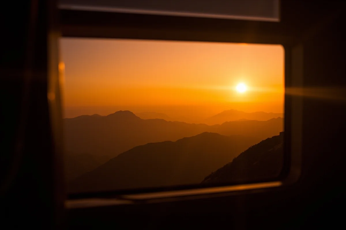 Sunset view from tour bus window with silhouetted mountains