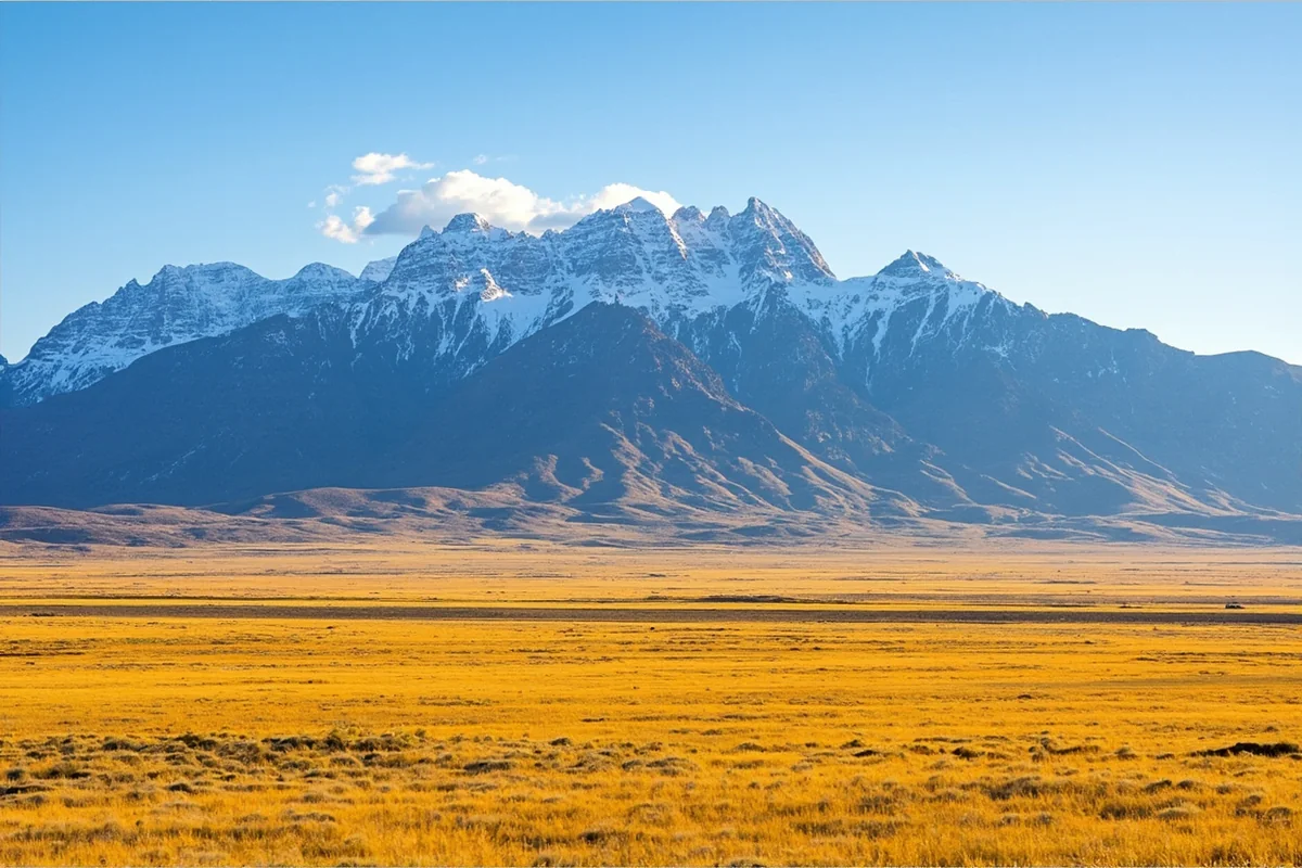 Sweeping vista of Montana's Rocky Mountain Front near Choteau, showing dramatic peaks rising from golden prairie
