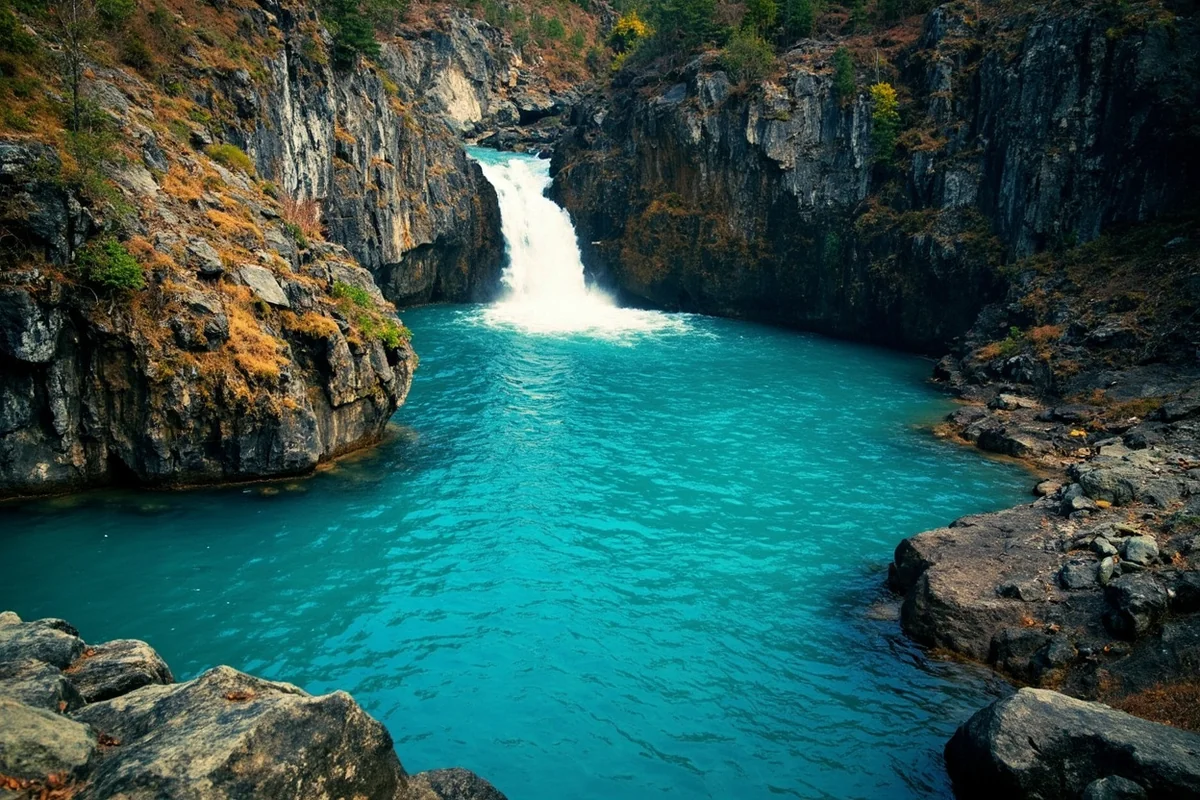 Turquoise pool at base of Pintler Falls with rocky shoreline visible